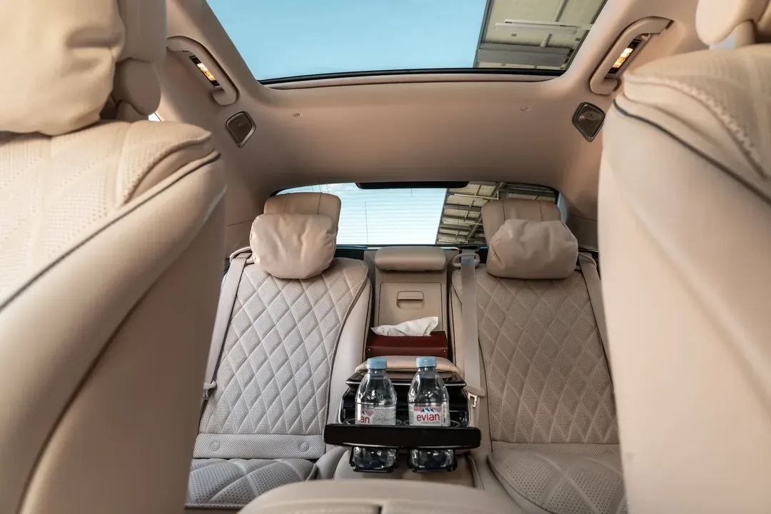 Cabine arrière d'une berline de luxe, sièges en cuir crème et toit panoramique