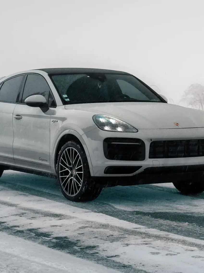 Porsche Cayenne blanc de la flotte Noctis sur une route enneigée